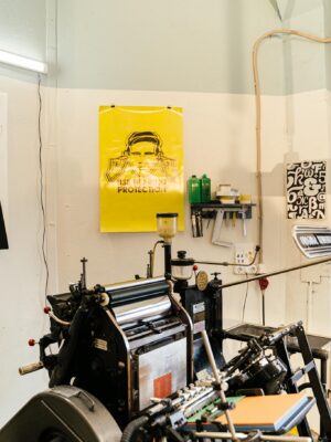 A detailed view of a professional printing press setup in a studio, highlighting equipment and posters.