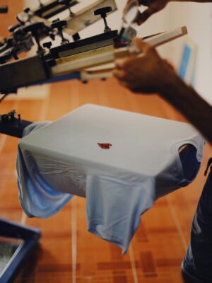 Close-up of a man using a T-shirt printing machine indoors.