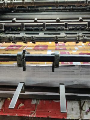 Close-up of an industrial printing machine processing paper sheets in a factory setting.
